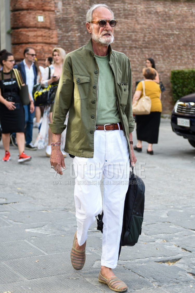 Men's spring/summer/fall outfit with plain silver sunglasses, plain olive green shirt jacket, plain green t-shirt, plain brown leather belt, and multi-colored striped espadrilles.