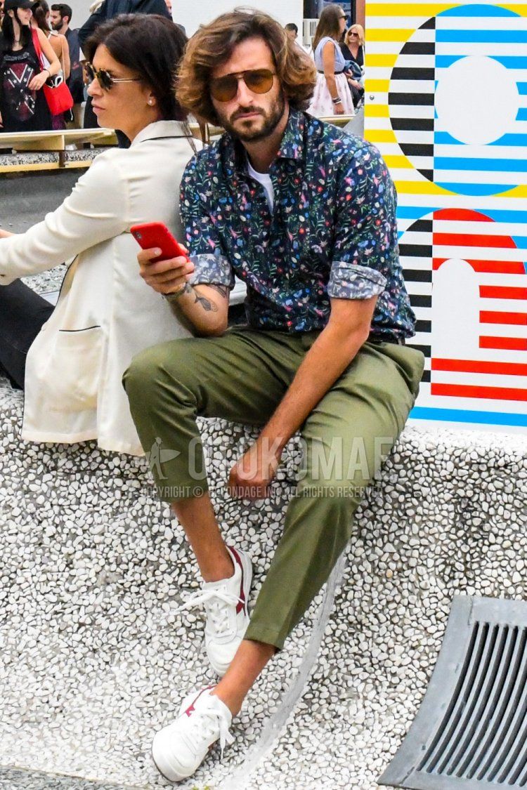 Men's spring/summer coordinate and outfit with plain sunglasses, navy botanical shirt, olive green plain ankle pants, olive green plain cotton pants, and white low-cut sneakers by Diadora.