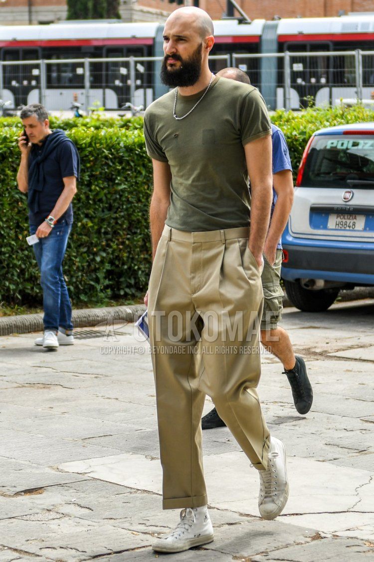 Men's spring and summer coordinate and outfit with plain olive green t-shirt, plain beige chinos, plain beige beltless pants, and Converse All Star white high-cut sneakers.