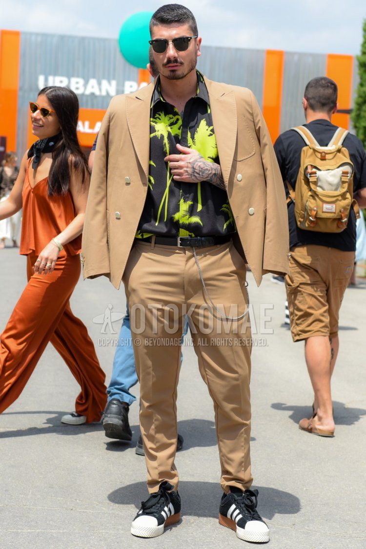 Men's spring, summer, and fall outfits with plain black sunglasses, MSGM black and yellow botanical shirt, plain black leather belt, Adidas black low-cut sneakers, and plain beige/brown suit.