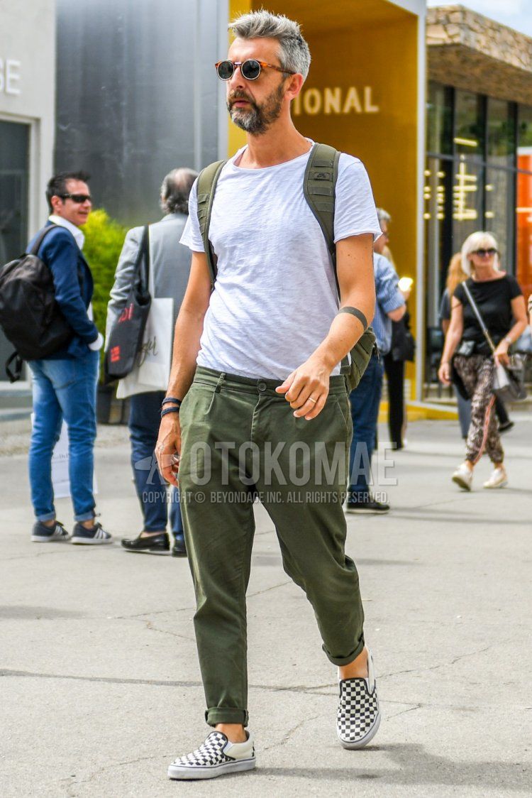 Men's summer coordinate and outfit with plain black-orange sunglasses, plain gray t-shirt, plain olive green chinos, Vans white and black slip-on sneakers, and plain olive green backpack.