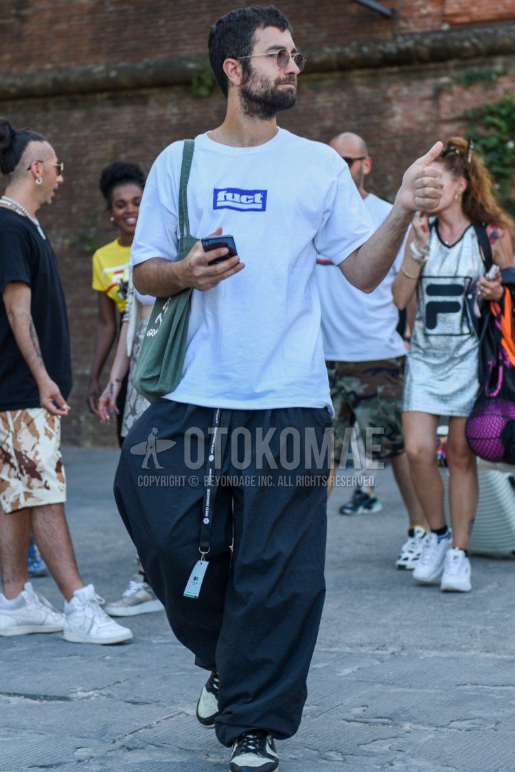 白ワンポイントのTシャツ、グレー無地のスラックス、ナイキの白・黒ローカットのスニーカーを合わせた夏のメンズコーデ・着こなし。