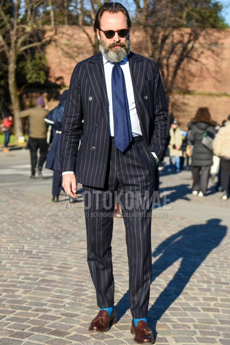 Men's spring and fall outfit with brown tortoiseshell sunglasses from Boston, plain white shirt, plain light blue socks, brown tassel loafer leather shoes, navy striped suit, and plain navy tie.