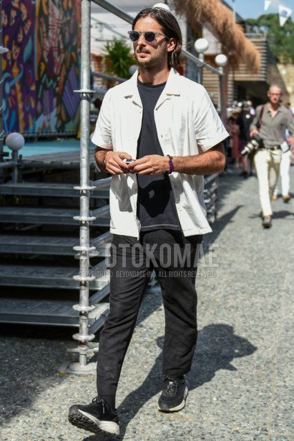 Men's spring/summer coordinate and outfit with clear solid sunglasses, short sleeve open collar solid white shirt, solid black t-shirt, solid black cotton pants, solid black socks, and black low-cut sneakers.