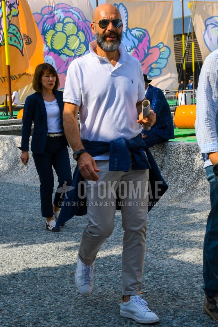 Men's spring/summer coordinate and outfit with Ray-Ban aviator teardrop plain silver sunglasses, Polo Ralph Lauren plain white polo shirt, beige plain chinos and white low-cut sneakers.