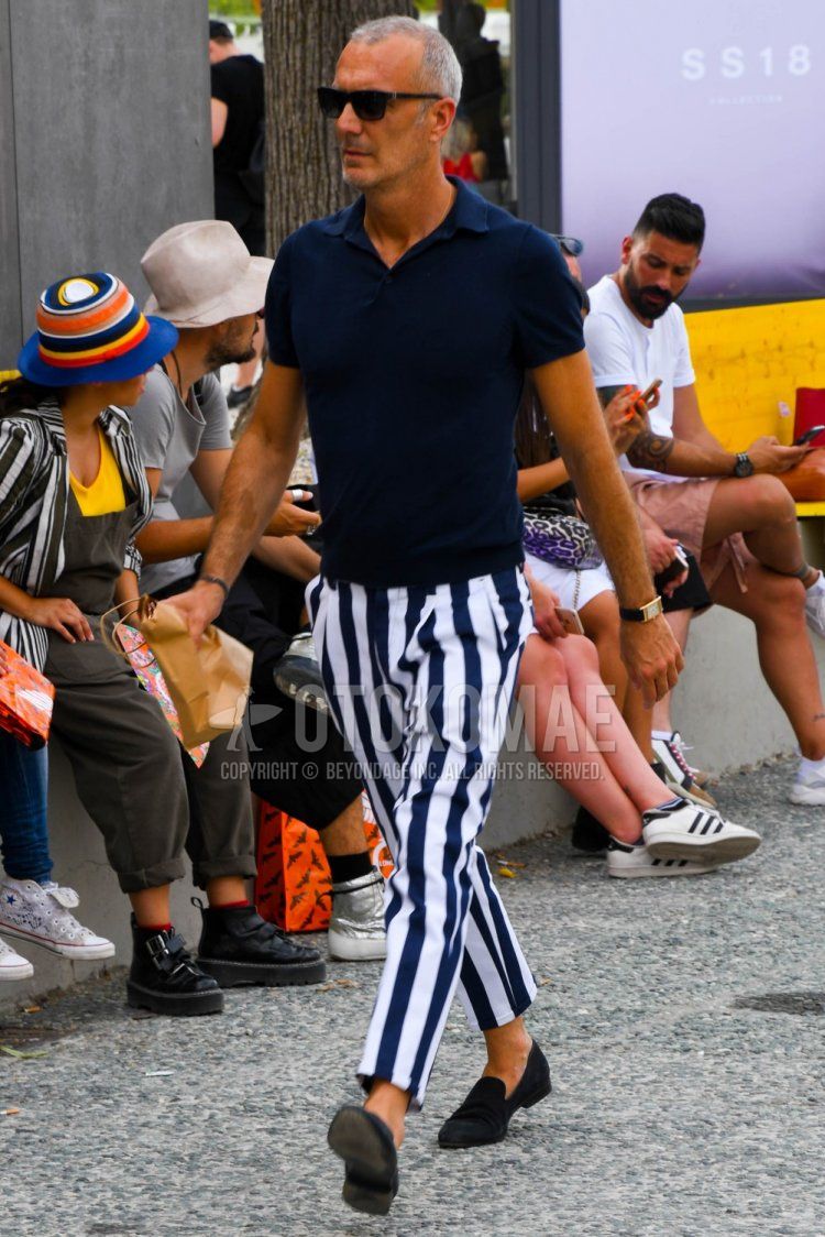 Men's spring and summer coordinate and outfit with plain black sunglasses, plain navy polo shirt, white and navy striped cotton pants, white and navy striped cropped pants, and suede navy loafer leather shoes.