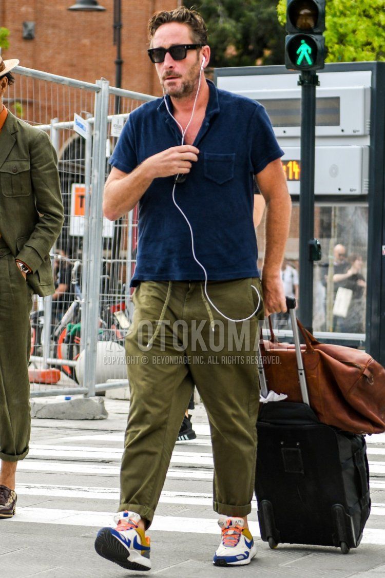 Men's summer coordinate and outfit with plain sunglasses, plain navy polo shirt, plain olive green easy pants, plain chinos, and Nike white low-cut sneakers.
