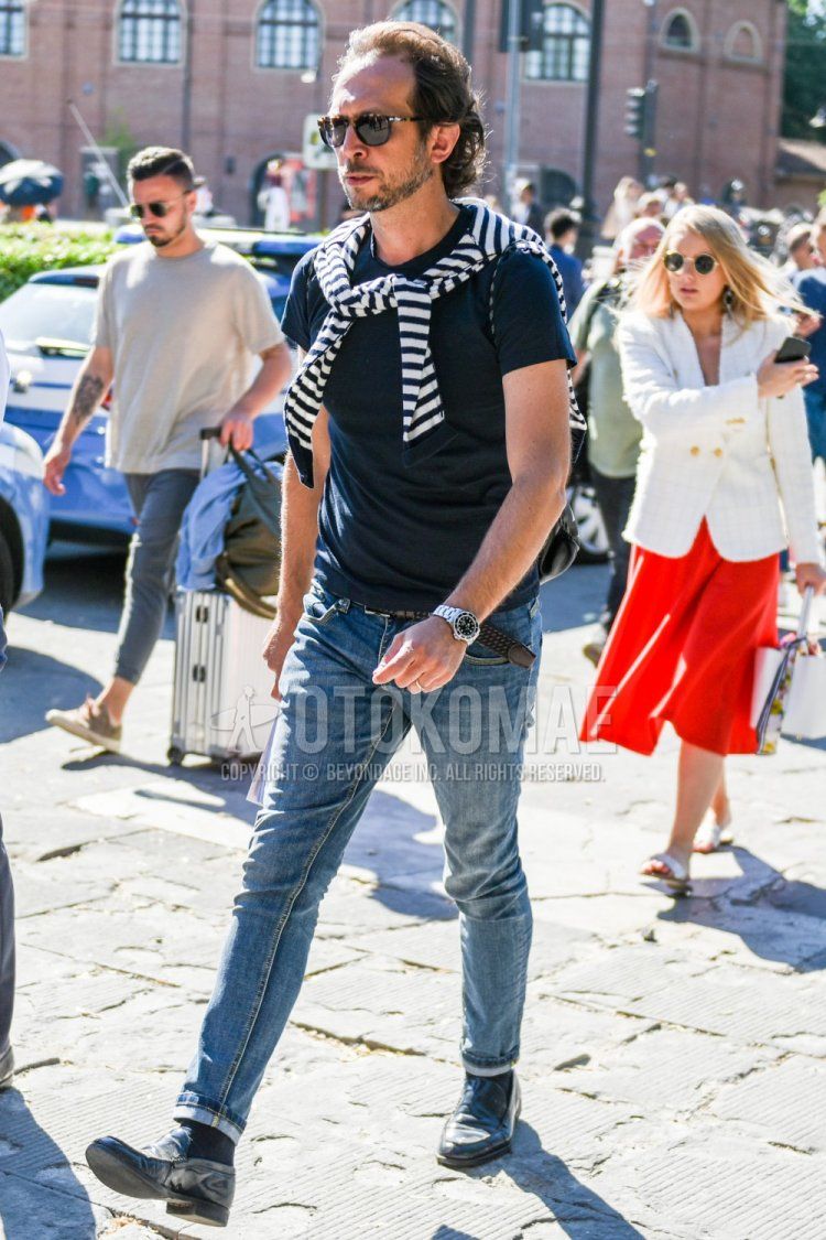 Summer men's coordinate and outfit with brown tortoiseshell sunglasses, plain navy t-shirt, white/black striped sweater, plain brown mesh belt, plain blue denim/jeans, plain black socks, and black coin loafer leather shoes.