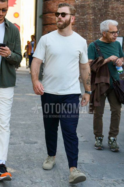 Men's summer coordinate and outfit with plain black sunglasses, plain light blue t-shirt, plain gray slacks, and green low-cut sneakers.