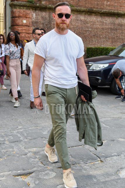 Men's summer coordinate and outfit with black tortoiseshell sunglasses, plain white t-shirt, plain olive green chinos, and beige low-cut sneakers.
