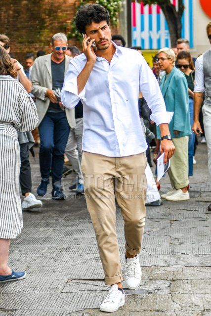 Men's spring, summer, and fall coordination and outfit with plain white shirt, plain beige chinos, and white low-cut sneakers.