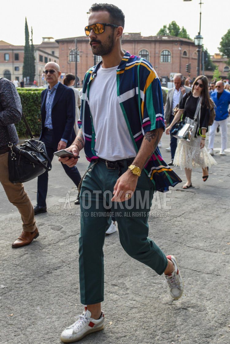 Men's spring/summer coordinate and outfit with solid black sunglasses, multi-colored top/inner shirt, solid white t-shirt, solid black mesh belt, solid black leather belt, solid green chinos, solid green cropped pants, and white low-cut sneakers.