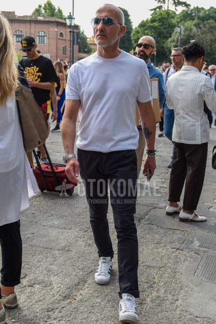 Men's summer coordinate and outfit with plain silver-blue sunglasses, plain white t-shirt, plain gray slacks, and Adidas Superstar white low-cut sneakers.
