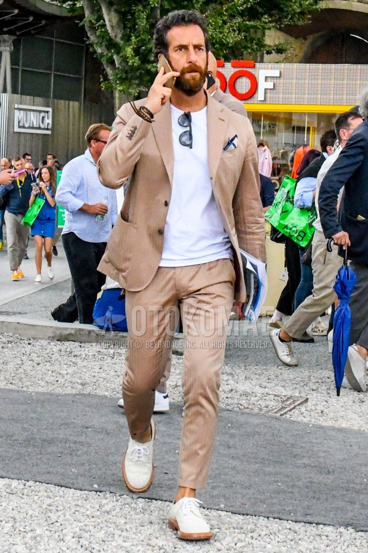 Men's spring and fall coordination and outfit with plain black sunglasses, plain white T-shirt, white wingtip leather shoes, and beige striped suit.