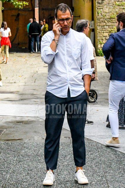 Men's spring/summer coordinate and outfit with plain black glasses, plain white shirt, dark gray plain slacks, and Alexander McQueen white low-cut sneakers.