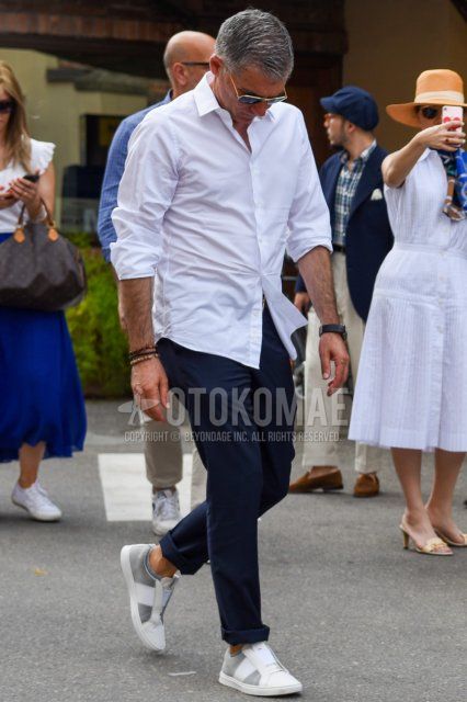 Men's spring/summer coordinate and outfit with plain gold/black sunglasses, plain white shirt, plain beige chinos, and white/gray low-cut sneakers.