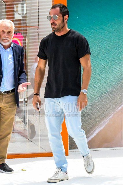 A summer men's coordinate and outfit with plain sunglasses, plain black t-shirt, plain white/blue denim/jeans, and white low-cut sneakers.