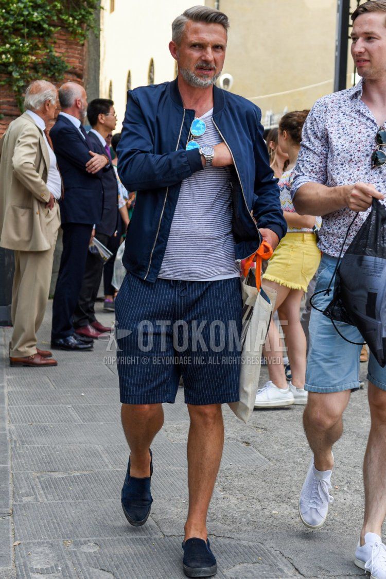 Men's spring, summer, and fall coordinate and outfit with plain navy MA-1, white and black striped T-shirt, navy striped shorts, and navy slip-on sneakers.