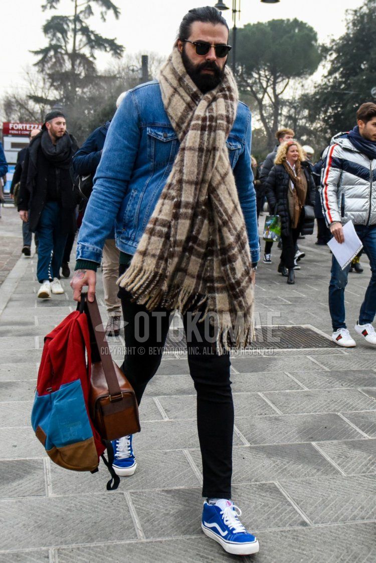 Winter men's coordinate and outfit with solid color sunglasses, brown checked scarf/stall, solid color blue denim jacket, solid color black skinny pants, blue high-cut sneakers by Vans, and multi-colored solid color backpack.