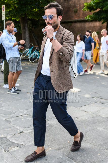 Men's spring and fall coordinate and outfit with plain silver sunglasses, plain brown tailored jacket, plain white t-shirt, plain navy ankle pants, and brown coin loafer leather shoes.
