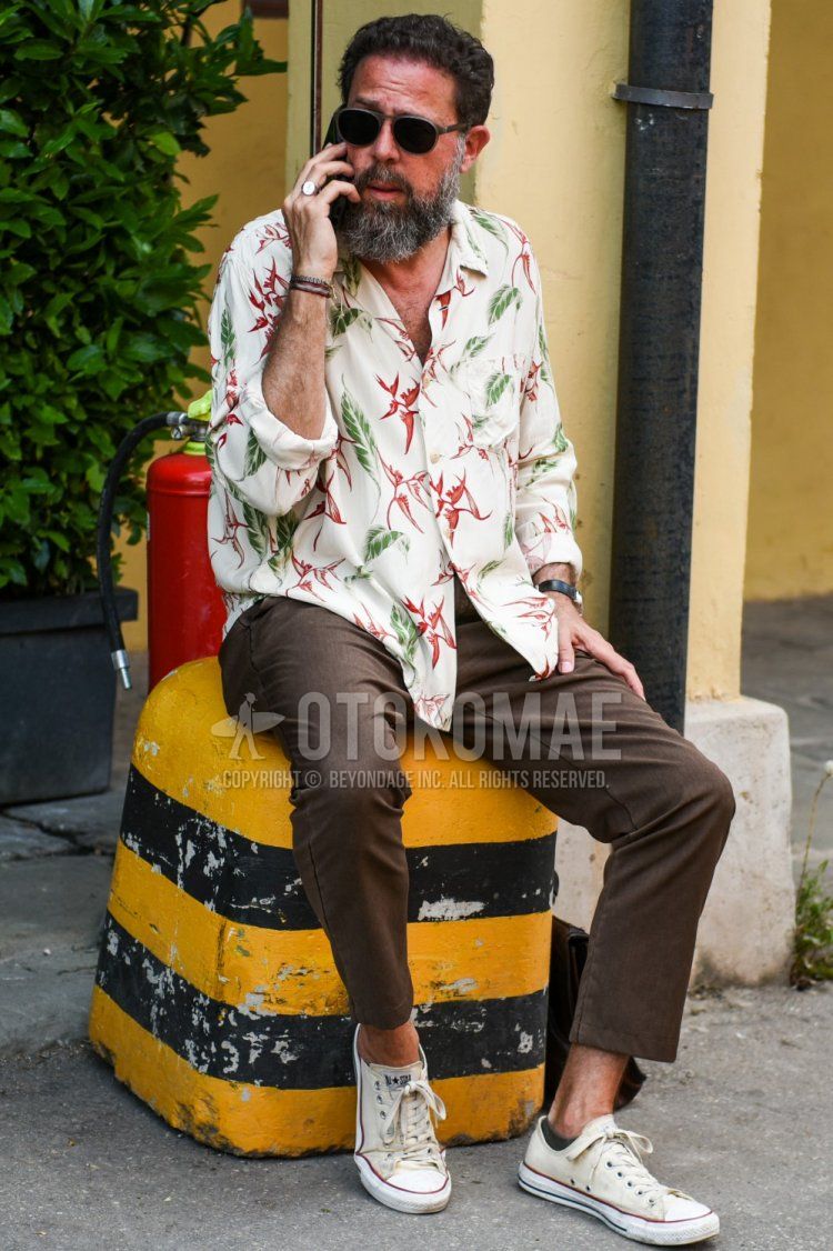 Men's spring/summer coordinate and outfit with clear/gray solid color sunglasses, white top/inner shirt, brown solid color slacks, and Converse All Star beige low-cut sneakers.