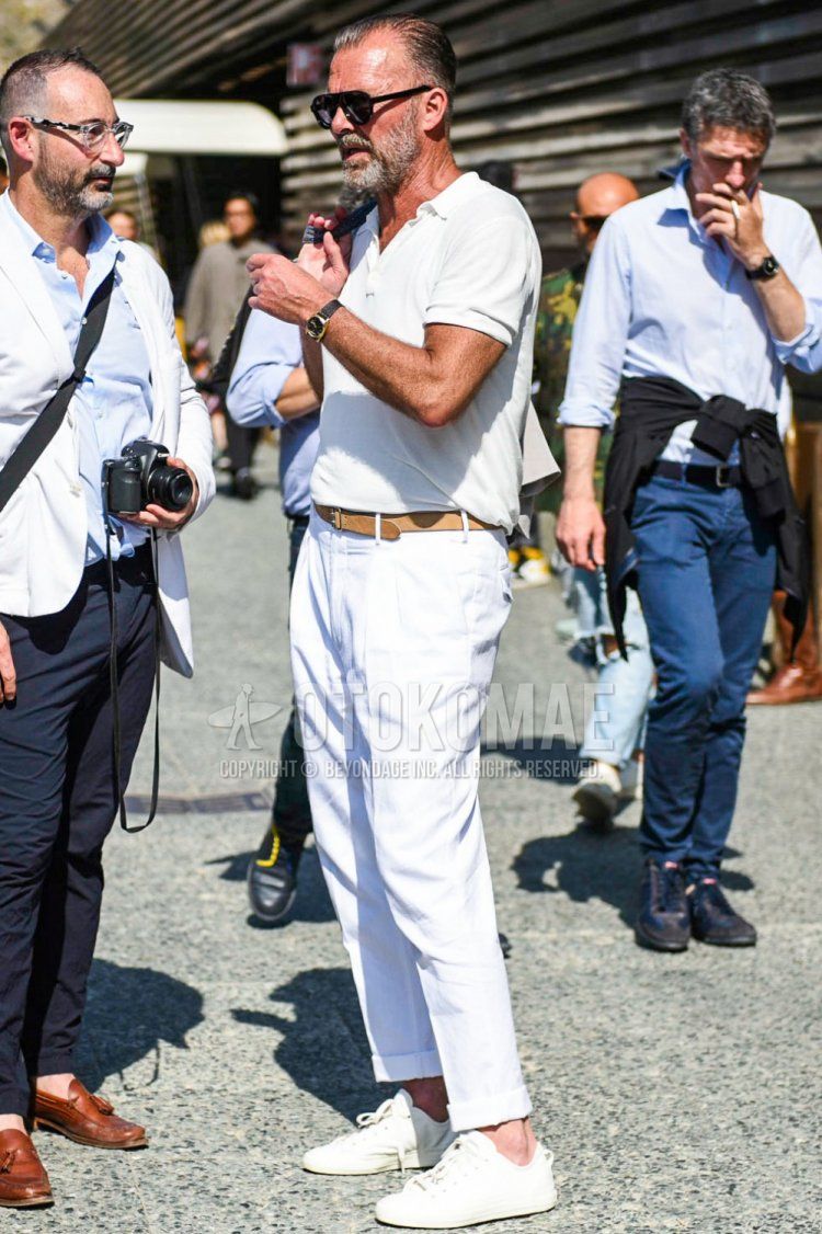 Men's spring/summer coordinate and outfit with plain black sunglasses, knit plain white polo shirt, plain brown leather belt, plain white cotton pants, and white low-cut sneakers.