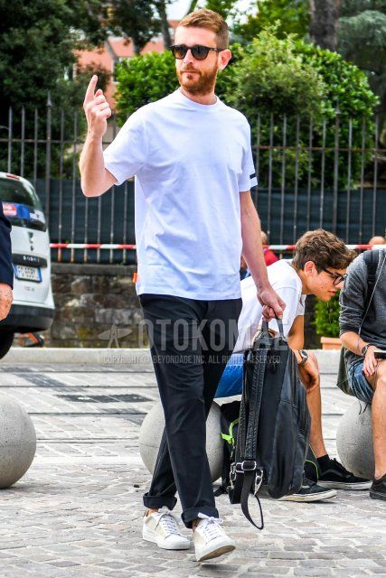 A summer men's coordinate and outfit with plain white sunglasses, plain white t-shirt, plain black cotton pants, white low-cut sneakers, and plain black backpack.