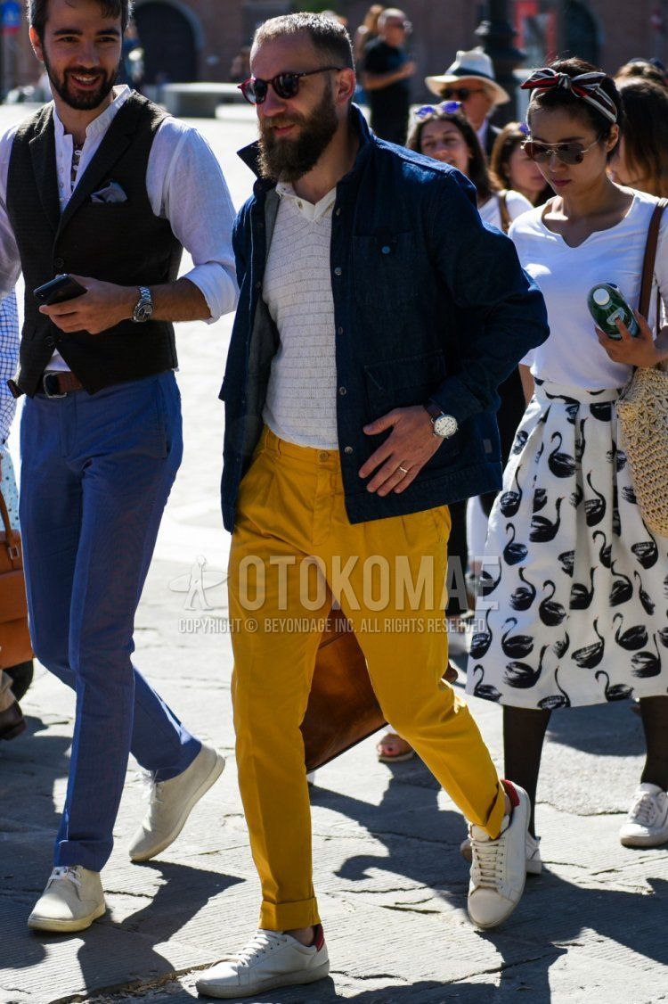 Men's spring and fall coordinate and outfit with brown tortoiseshell sunglasses, plain navy denim jacket, white top/inner polo shirt, plain beige chinos, and white low-cut sneakers.