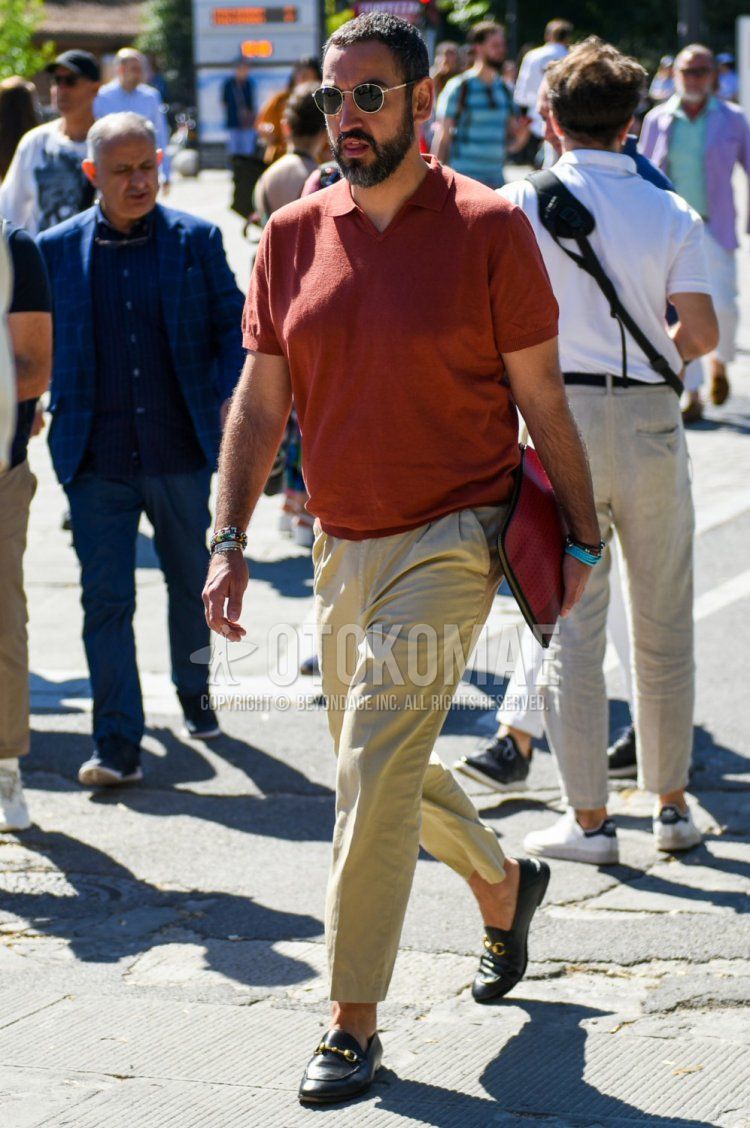 A summer men's outfit and outfit with round black and gold solid sunglasses, solid orange polo shirt, solid beige chinos and Gucci black bit loafer leather shoes.