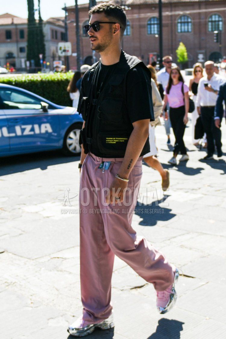 A summer men's outfit and outfit with plain black sunglasses, plain black t-shirt, plain gilet, plain pink tape belt, plain pink cotton pants, and Raf Simons Adidas Oswego pink/silver low-cut sneakers.