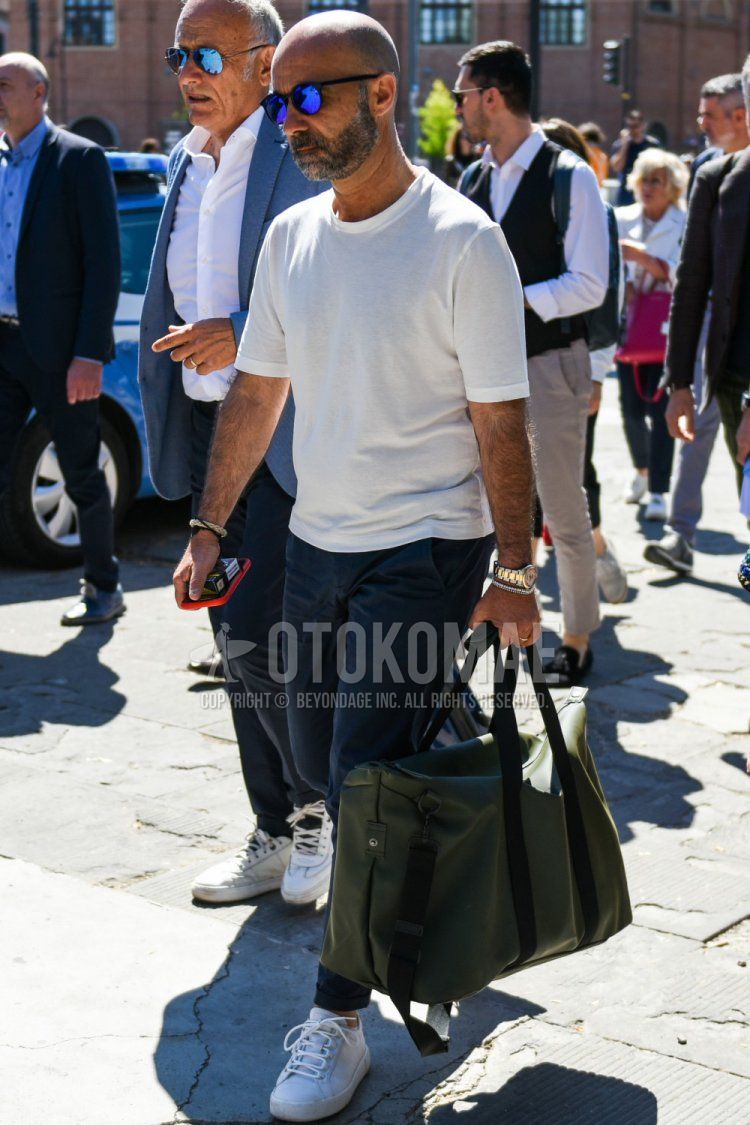 Men's summer coordinate and outfit with plain black sunglasses, plain white t-shirt, plain navy chinos, white low-cut sneakers, and plain olive green Boston bag.