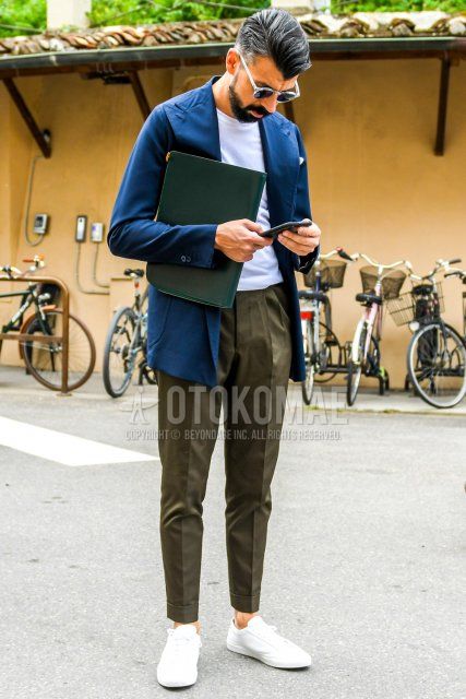 Men's spring, summer, and fall coordinate and outfit with clear solid sunglasses, navy solid tailored jacket, white solid t-shirt, olive green solid slacks, olive green solid ankle pants, and white low-cut sneakers.