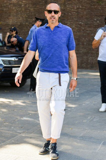 Men's spring and summer coordinate and outfit with brown tortoiseshell sunglasses, plain blue polo shirt, plain white cotton pants, and Adidas black and light blue low-cut sneakers.