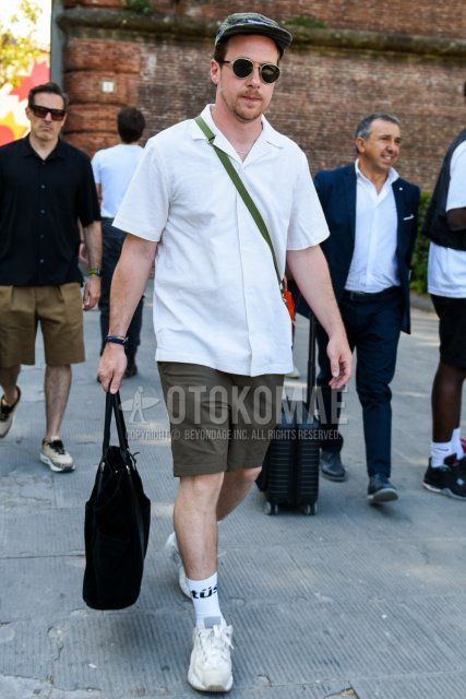 Summer men's coordinate and outfit with olive green solid color jet cap, solid color black sunglasses, open collar solid color white shirt, solid color gray shorts, white graphic socks, white low cut sneakers and solid color black tote bag.