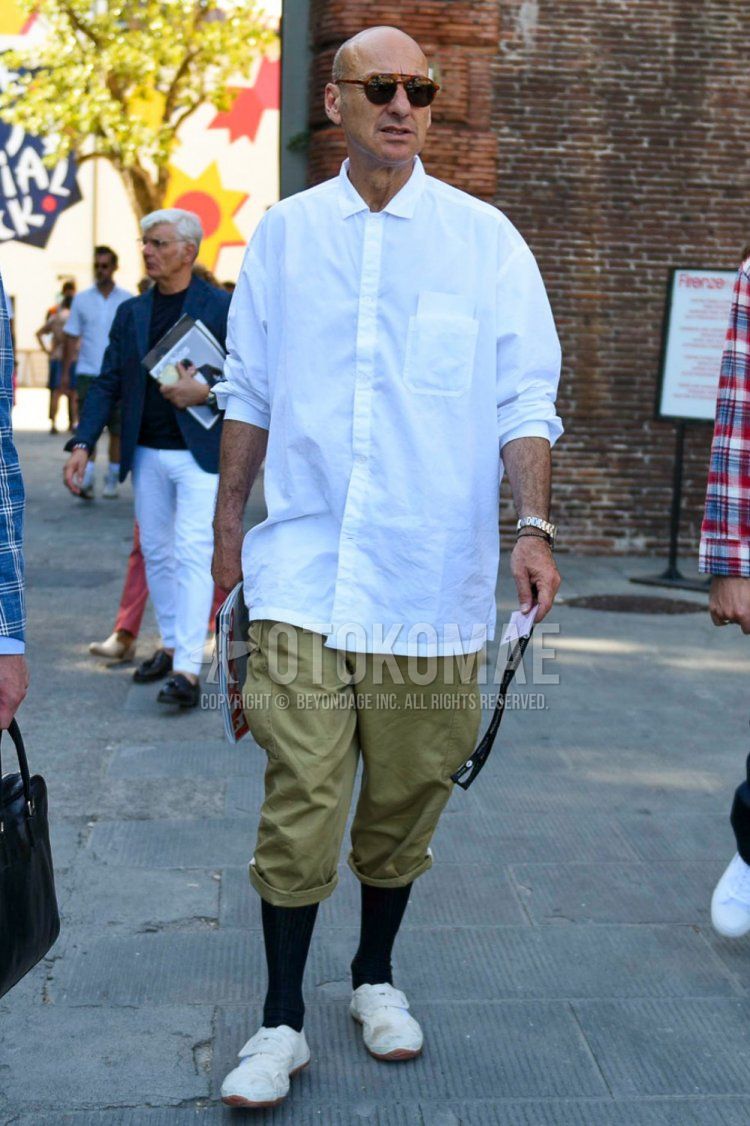 Men's spring, summer, and fall coordinate and outfit with brown tortoiseshell sunglasses, plain white shirt, plain beige cotton pants, plain black socks, and white low-cut sneakers.