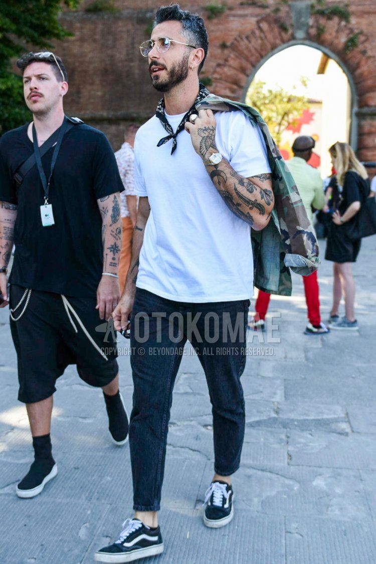 Summer men's coordinate and outfit with plain gold glasses, black stole bandana/neckerchief, plain white t-shirt, plain dark gray denim/jeans, and Vans Old School black low-cut sneakers.