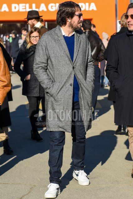 Men's fall/winter coordinate and outfit with solid black sunglasses, solid gray chester coat, solid blue sweater, solid white shirt, solid navy denim/jeans, and white low-cut sneakers by Diadora.