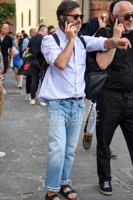 Men's spring/summer coordinate and outfit with plain black Ray-Ban sunglasses, white/light blue striped shirt, plain black leather belt, plain light blue damaged jeans, and black leather sandals.