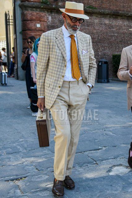 Men's spring/summer/fall outfit with solid beige hat, solid black glasses, beige checked tailored jacket, solid white shirt, solid beige slacks, brown coin loafer leather shoes, solid brown briefcase/handbag, orange regimental tie Outfit.