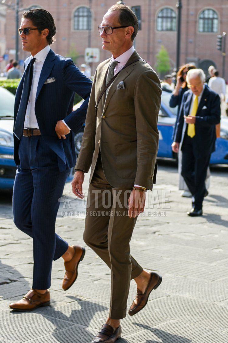 Men's spring and fall coordinate and outfit with plain glasses, plain white shirt, brown coin loafer leather shoes, plain olive green suit, and plain olive green tie.