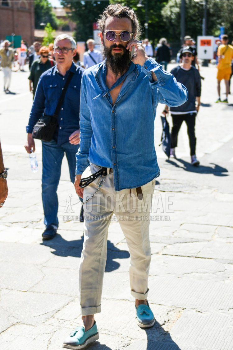 Men's spring/summer outfit with solid gold/black sunglasses, solid blue bandana/neckerchief, solid blue shirt, solid brown leather belt, solid beige chinos, and light blue slip-on sneakers.