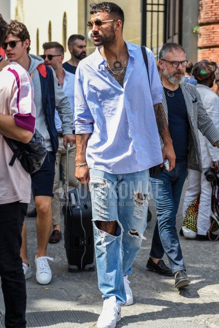 Men's spring, summer, and fall coordinate and outfit with plain gold sunglasses, light blue striped shirt, light blue plain damaged jeans, and white low-cut Nike sneakers.