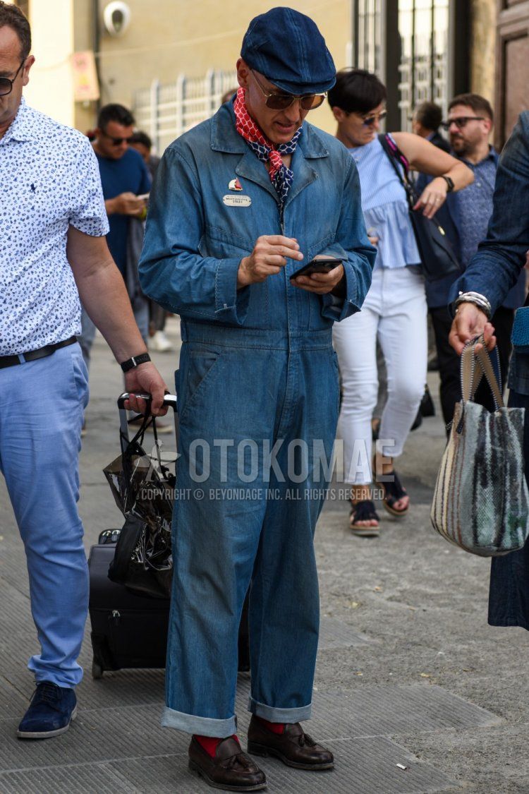 Men's spring/fall outfit with solid navy cap, solid gold/brown sunglasses, solid red/navy bandana/neckerchief, solid blue jumpsuit, solid red socks, and brown tassel loafer leather shoes.