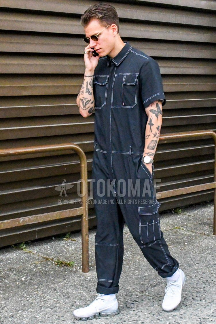Men's spring, summer, and fall coordinate and outfit with plain gold sunglasses, plain black jumpsuit, plain white socks, and Nike Air Vapormax white low-cut sneakers.