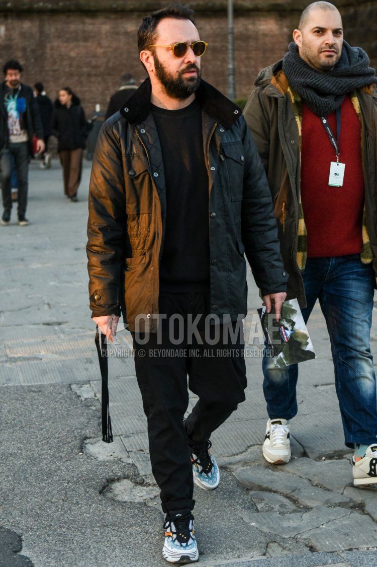 Men's fall/winter coordinate and outfit with solid beige sunglasses, solid black outerwear, solid black sweatshirt, solid black denim/jeans, and white low-cut sneakers.