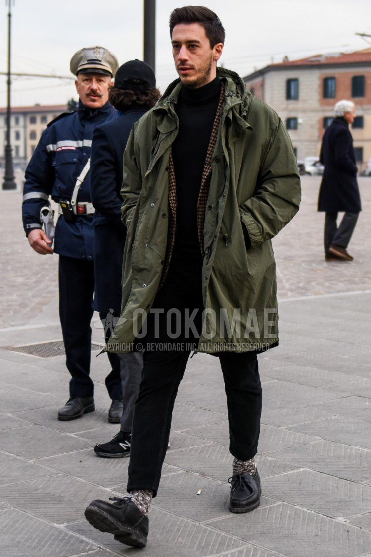 Men's fall/winter outfit and outfit with olive green solid color mod coat, black/brown checked tailored jacket, solid color black turtleneck knit, solid color black cotton pants, brown socks, black leather shoes.