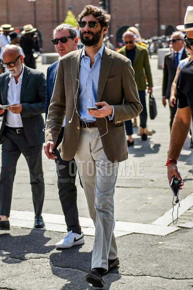 Men's spring and fall outfit with plain gold sunglasses, plain brown tailored jacket, plain light blue shirt, plain brown leather belt, plain gray slacks, and brown leather shoes.