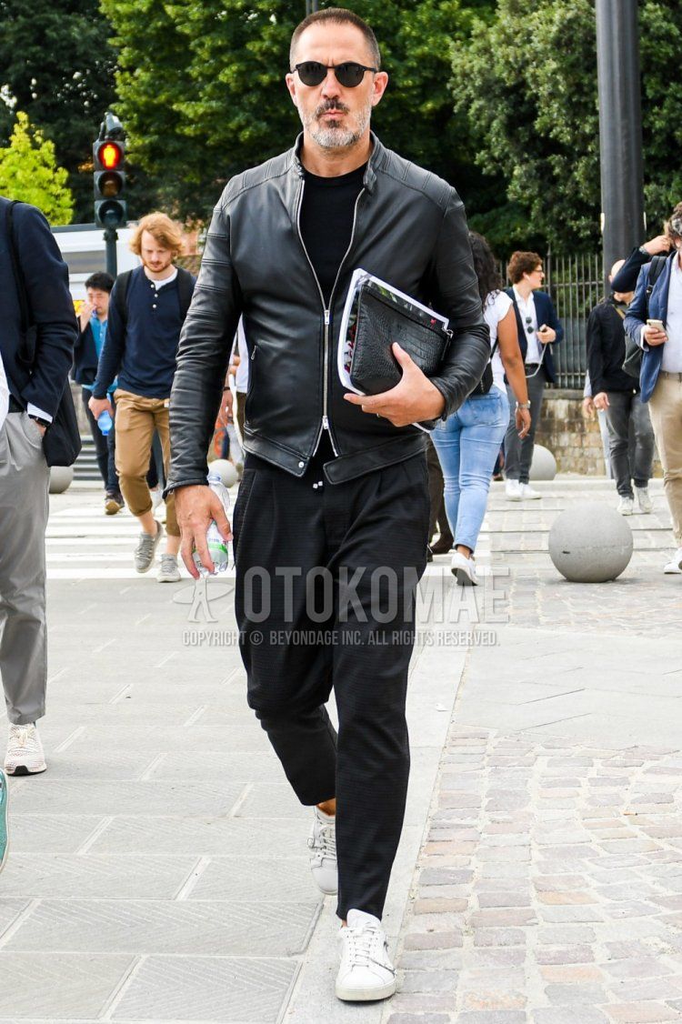 Men's spring and fall coordinate and outfit with solid color sunglasses, solid color black rider's jacket, solid color black t-shirt, solid color black ankle pants, solid color easy pants, and white low-cut sneakers.