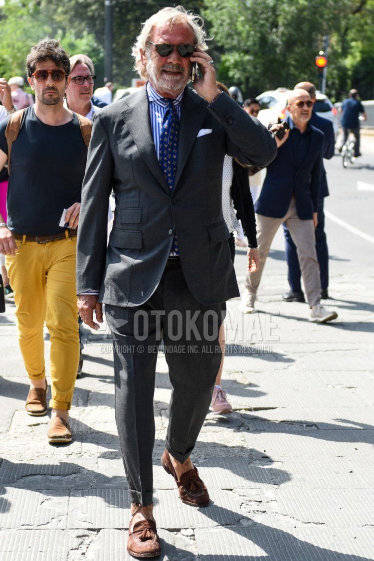 Men's spring/summer/autumn coordination and outfit with plain black sunglasses, blue/white striped shirt, brown tassel loafer leather shoes, dark gray plain suit, and blue tie tie.