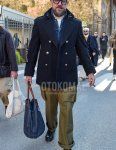 Men's fall/winter outfit with solid black glasses, solid black P coat, solid blue denim jacket, solid white turtleneck knit, solid beige cargo pants, black boots, and solid blue briefcase/handbag.